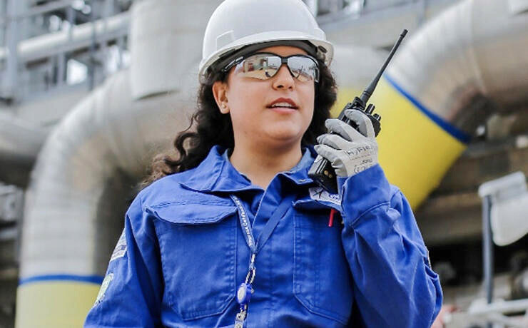 Woman wearing hard hat using a walkie-talkie.