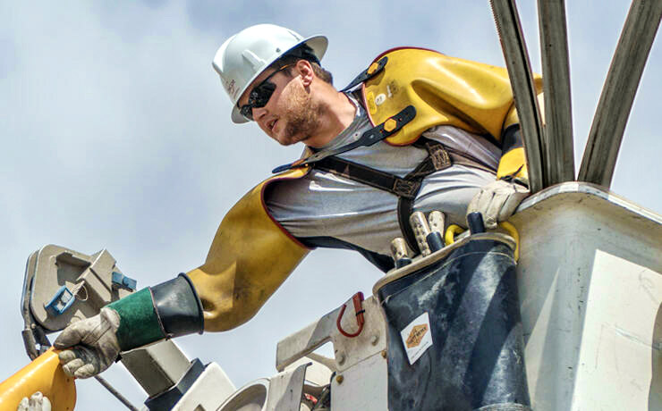 Electrical technician in cherry picker working on electrical lines.