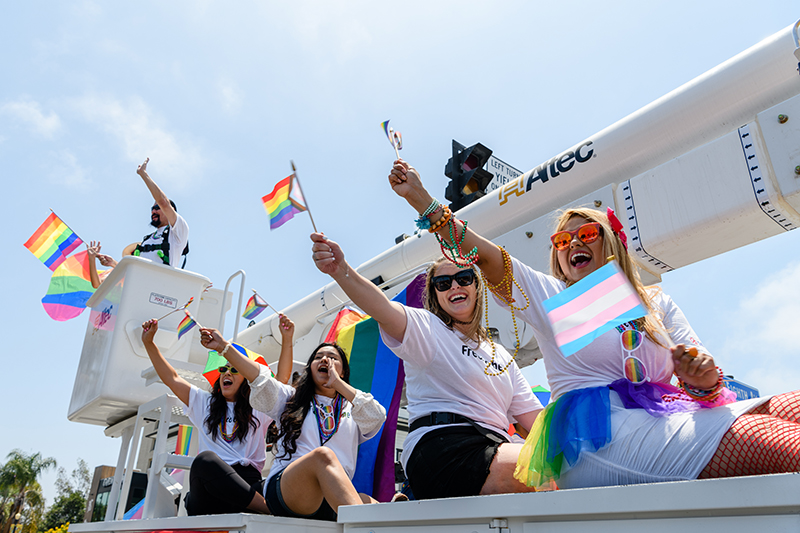 Sempra and SDG&E team members wave to the crowd from a bucket truck during the 2022 San Diego Pride parade