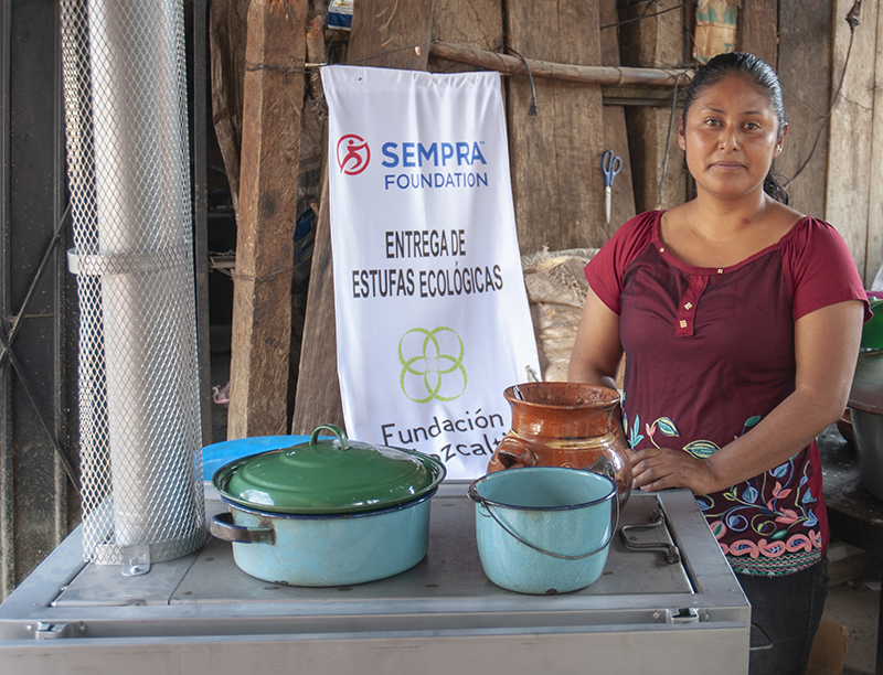A community member stands next to her new stove