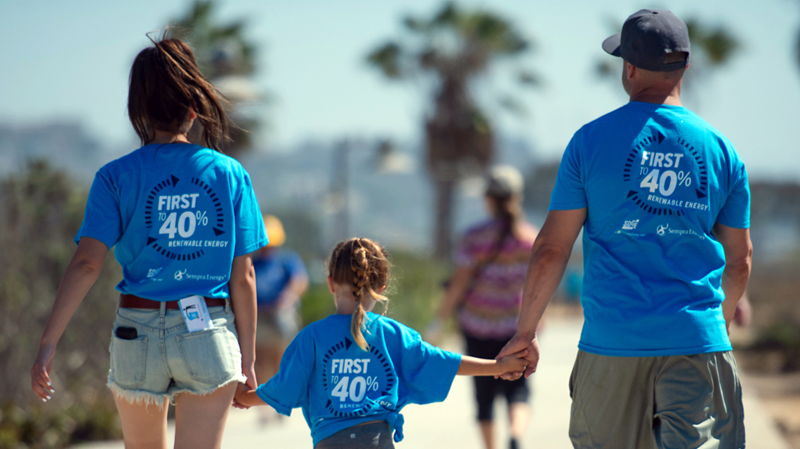 A family wearing celebratory shirts holding hands and walking