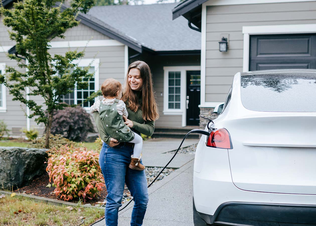 A mother and child charging their electric vehicle at their home