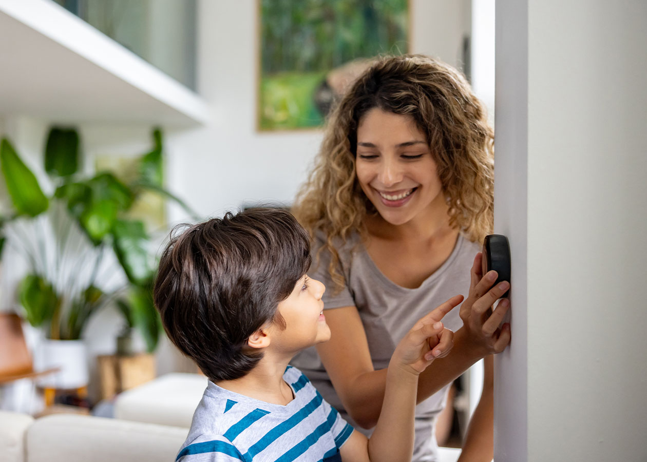 A mother and child adjusting a thermostat